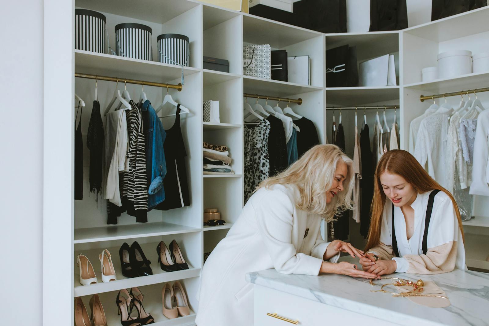 Senior and young woman enjoying a fashion consultation in a stylish boutique wardrobe setting.