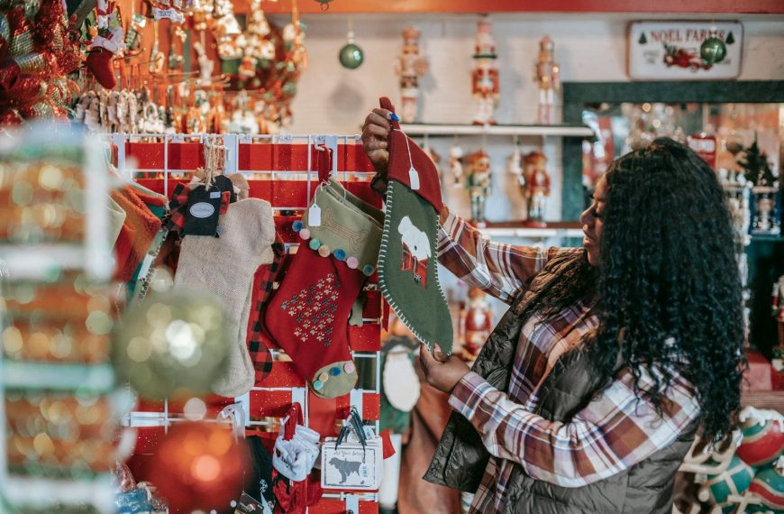 Side view of smiling African American female with Xmas sock in shop with decorative baubles and gifts