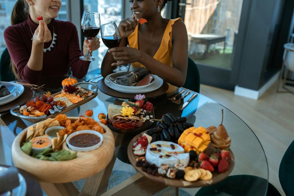 Two adults enjoy wine and a colorful charcuterie board indoors, embodying warmth and friendship.