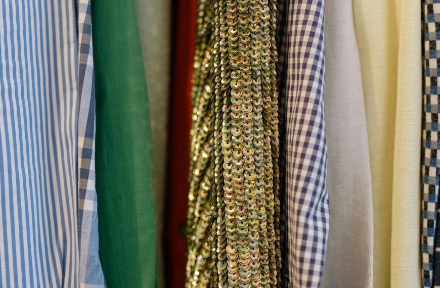 Close-up of assorted fabrics including sequined and patterned textiles on display in a retail shop.