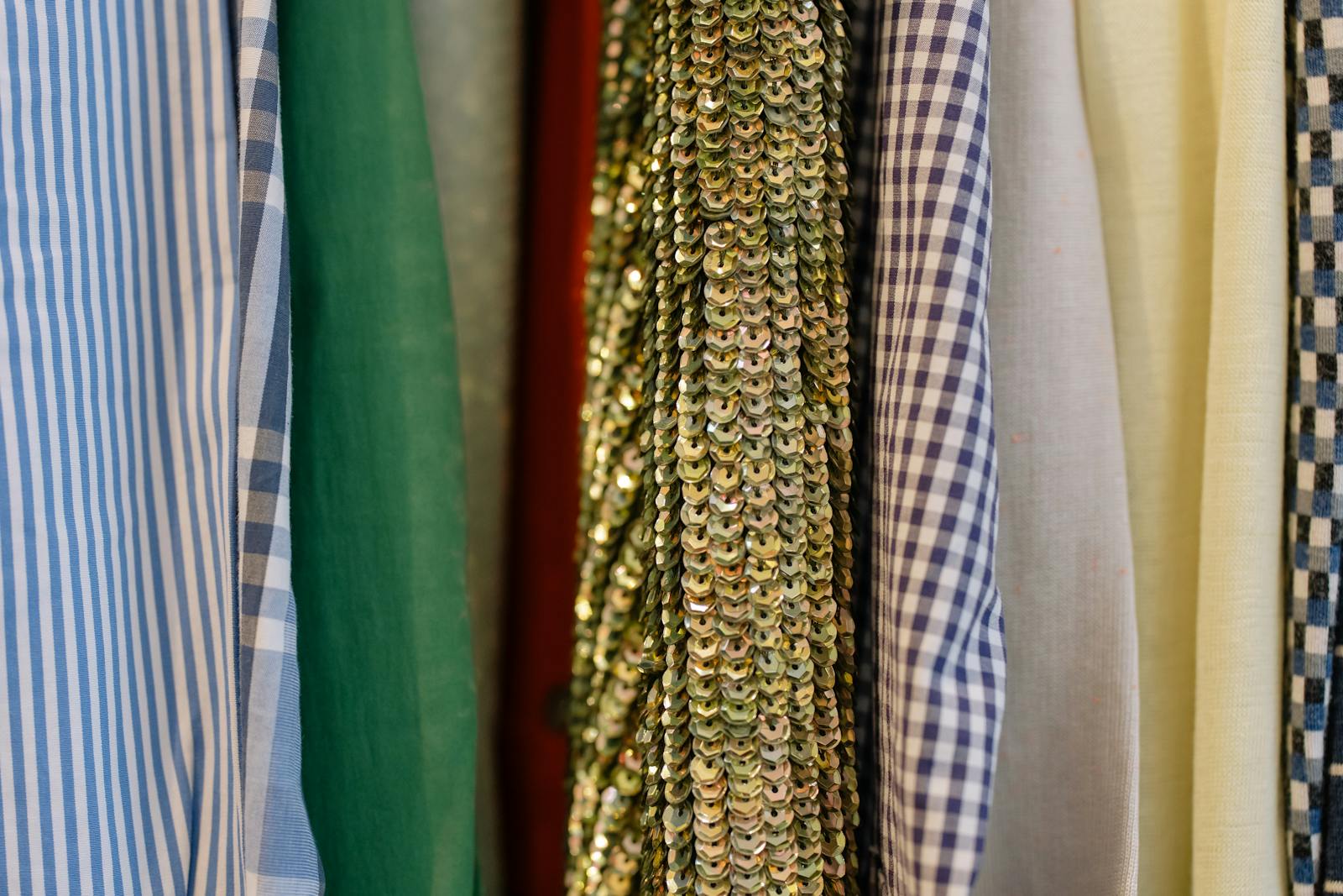 Close-up of assorted fabrics including sequined and patterned textiles on display in a retail shop.