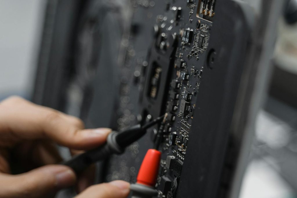 A technician uses tools to repair a circuit board, focusing on microelements.