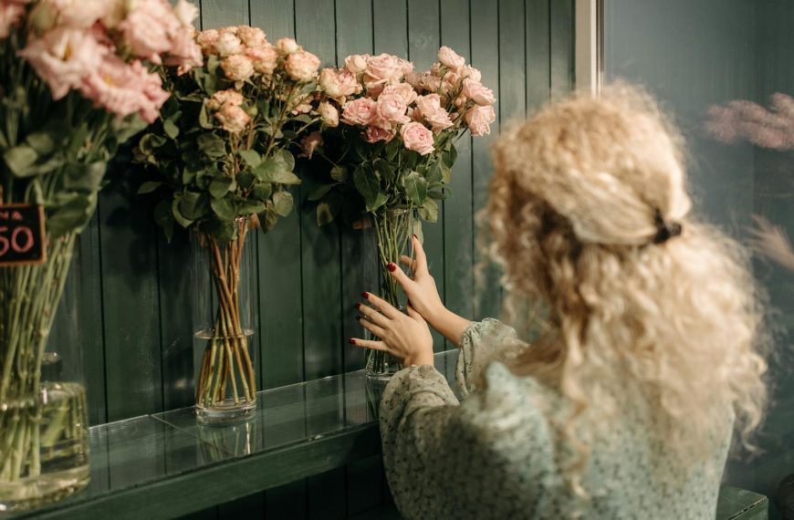 A florist arranges pink roses in vases on display in a flower shop.