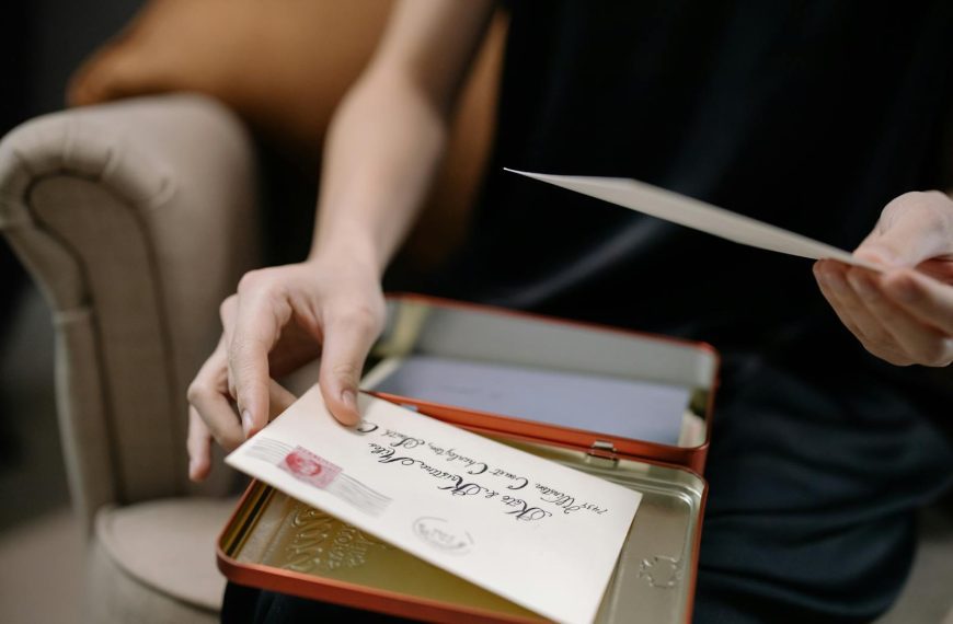 A person holds letters in a tin box, displaying vintage correspondence.