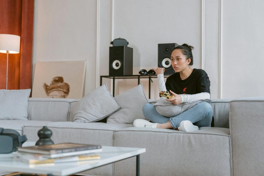 Young woman enjoying video games on a sofa in a stylish living room setting.