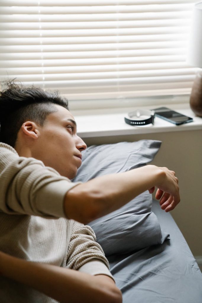 A teenager waking up and checking notifications on a smartphone in a cozy bedroom setting.
