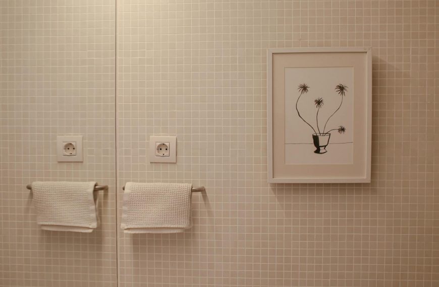 Elegant bathroom with framed art and textured towels on tiled wall.