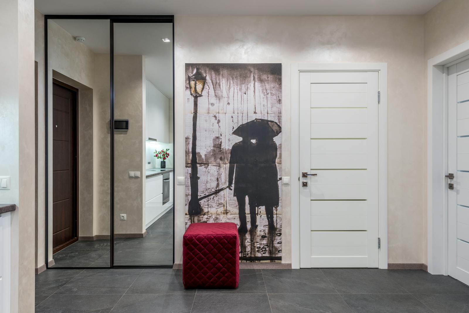 A modern hallway with chic decor, featuring a large mirror and captivating artwork.