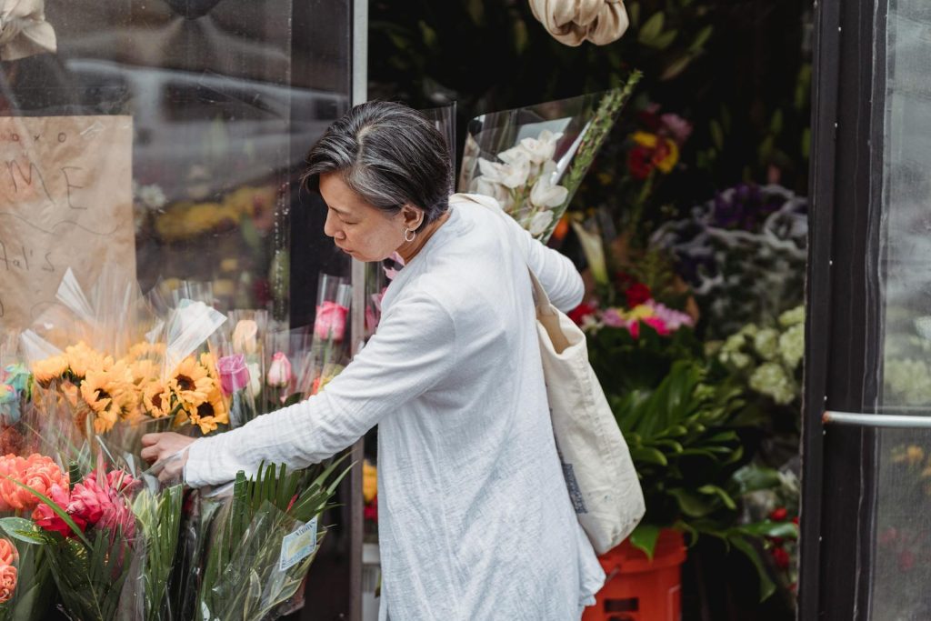 A woman carefully selects flowers from an outdoor florist for a special occasion.
