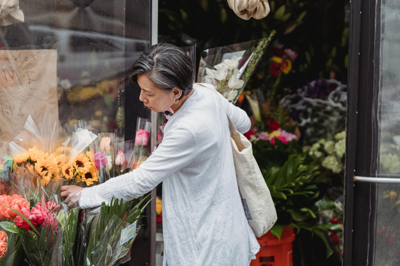 A woman carefully selects flowers from an outdoor florist for a special occasion.