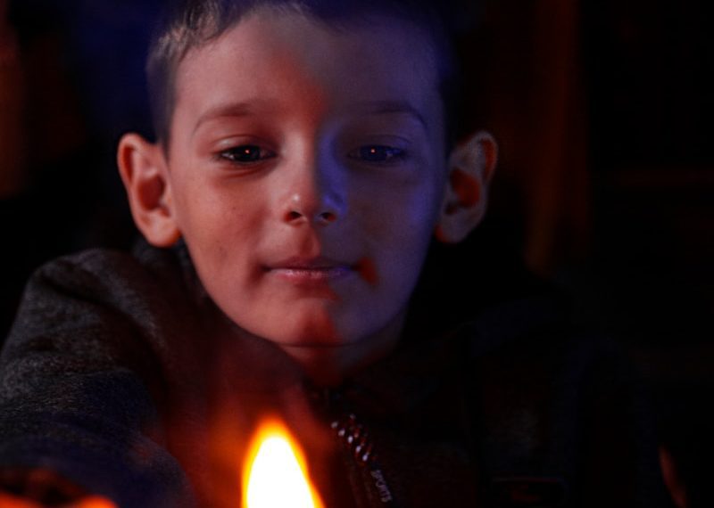 a young boy holding a lit candle in his hands