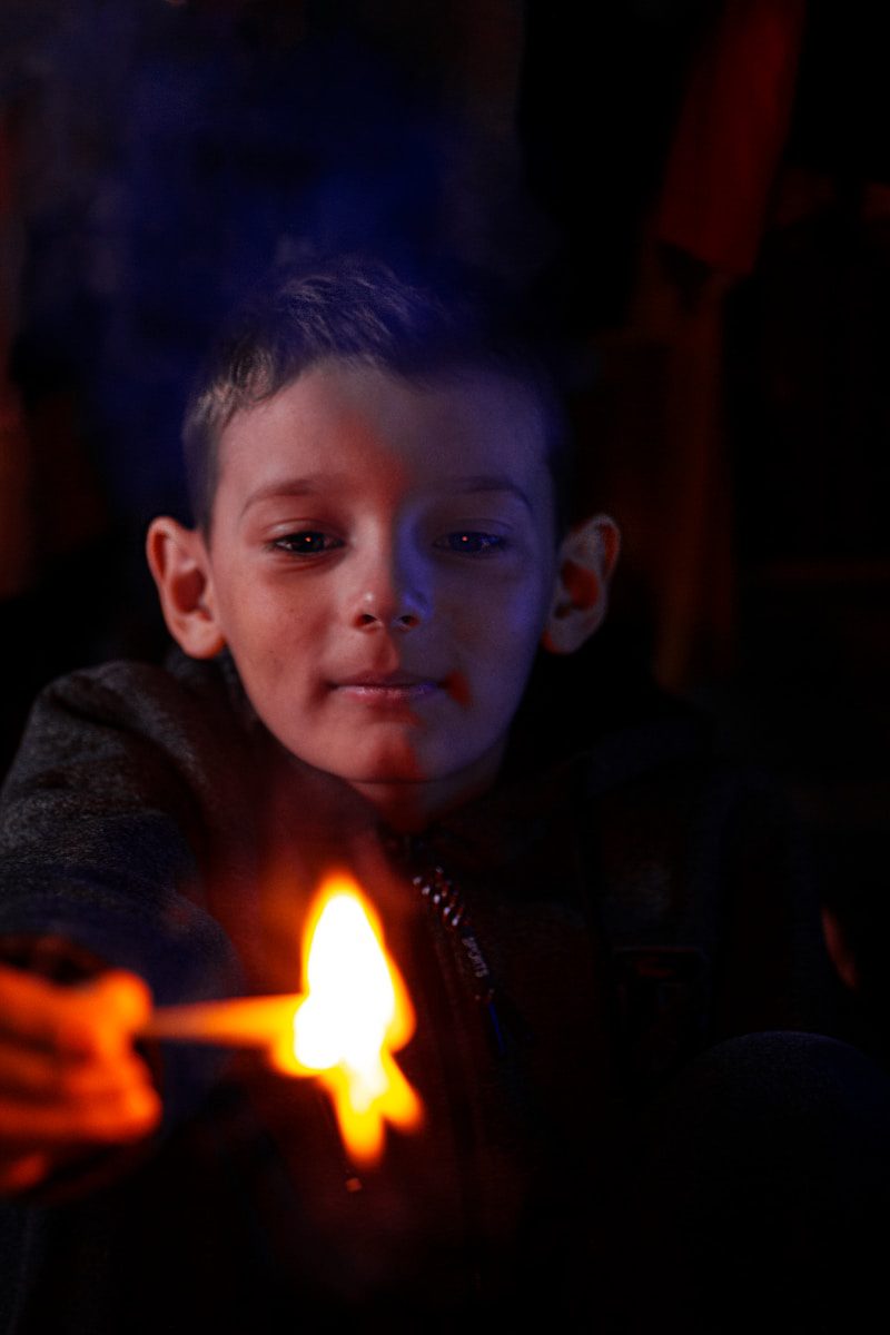 a young boy holding a lit candle in his hands