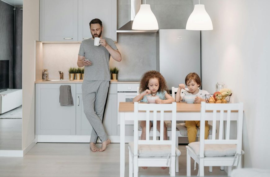 Father and children having breakfast in a modern kitchen. Cozy and casual family morning routine.