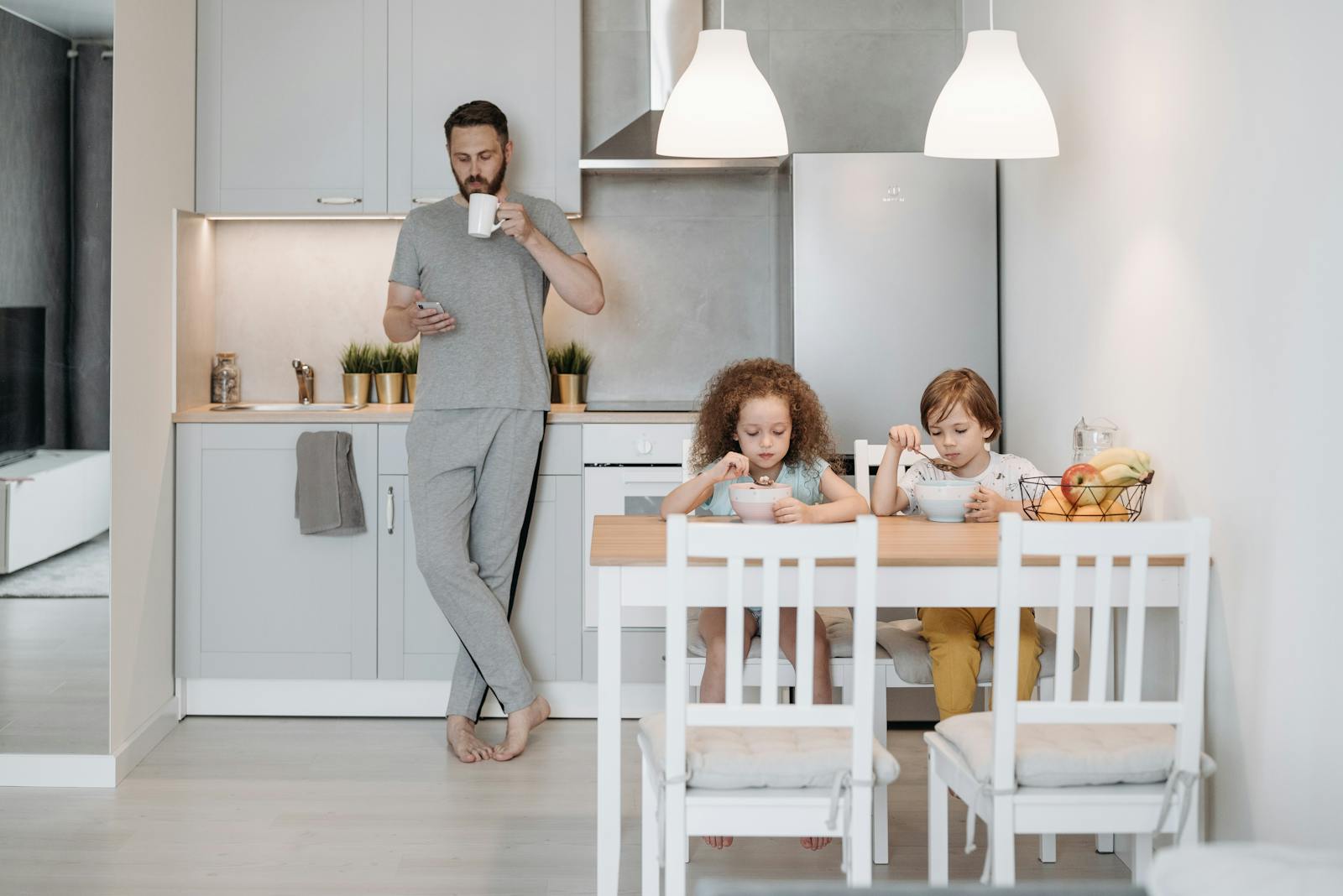 Father and children having breakfast in a modern kitchen. Cozy and casual family morning routine.