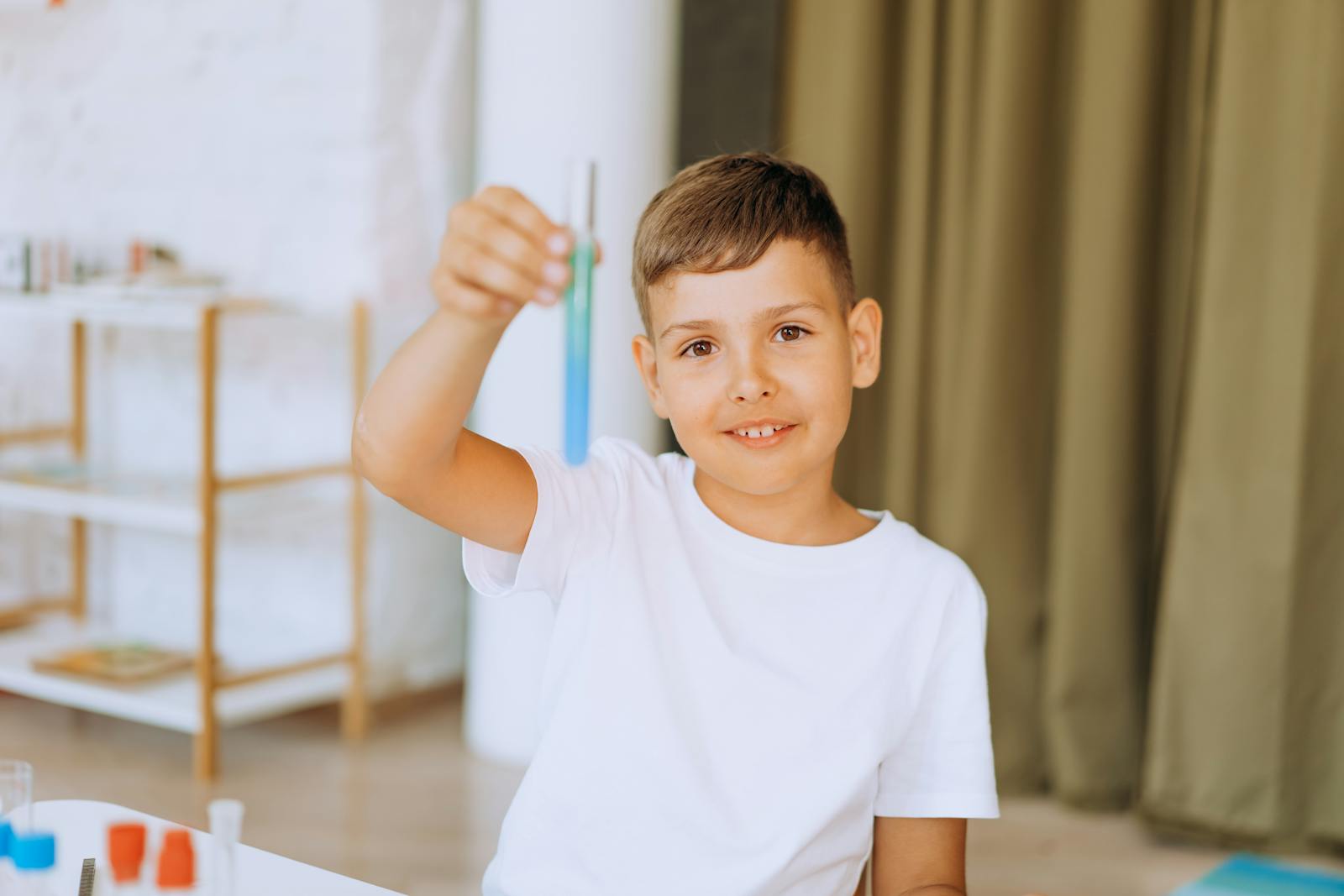 Smiling child holding test tube during a science experiment at home.