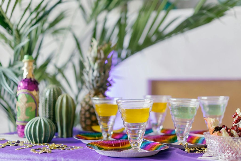 Vibrant table setting with tropical drinks, pineapples, and cacti for a festive atmosphere.