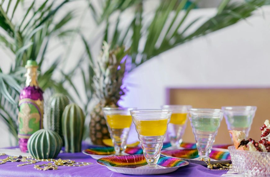 Vibrant table setting with tropical drinks, pineapples, and cacti for a festive atmosphere.