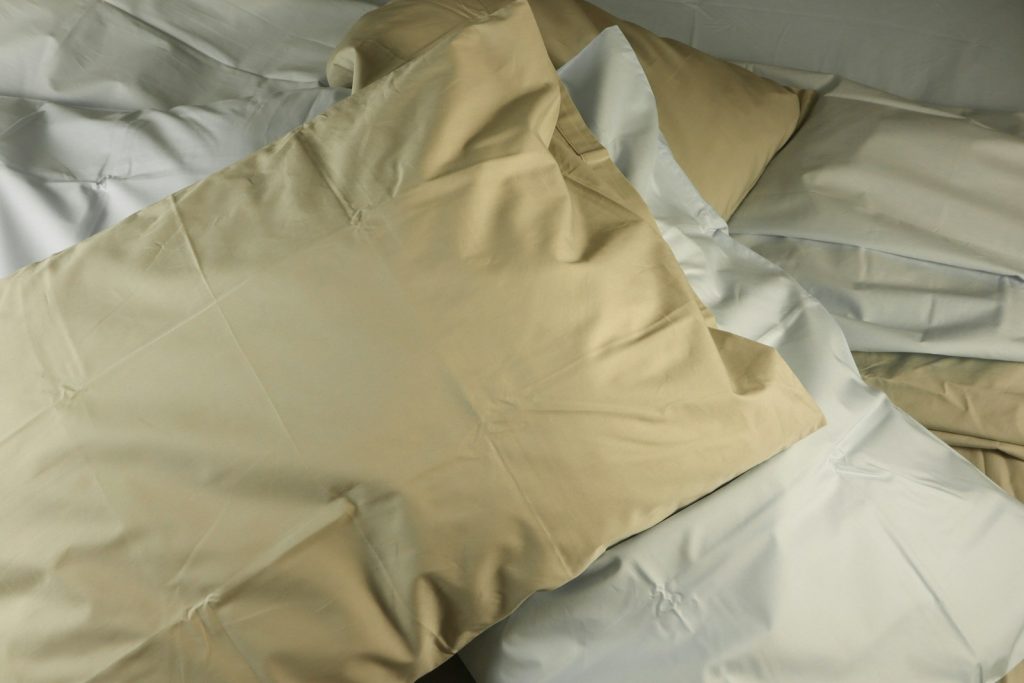 a pile of pillows sitting on top of a bed