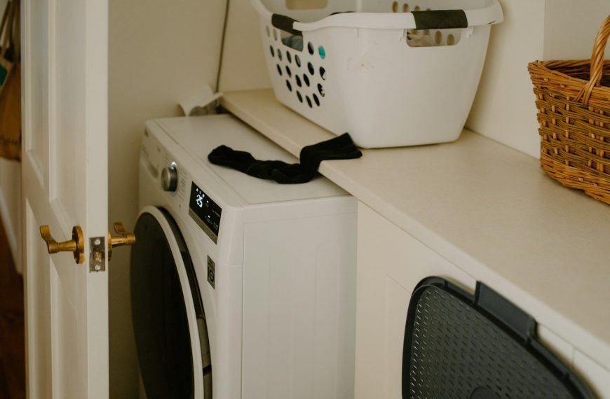 White washing machine with laundry basket and sock.