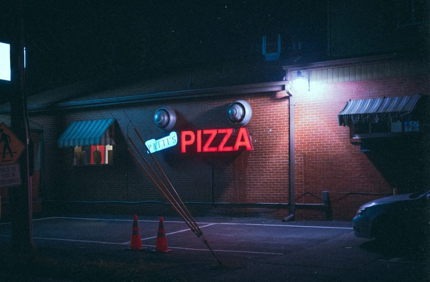 a pizza restaurant with a neon sign on the side of the building
