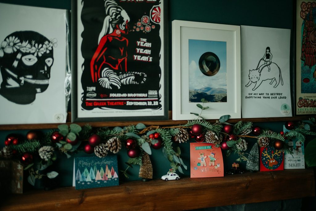 a mantel with christmas decorations and posters on it