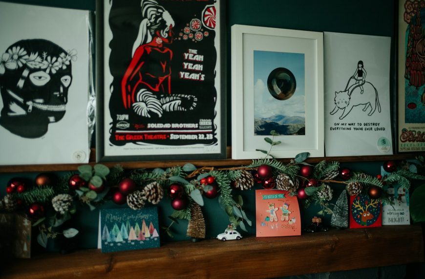 a mantel with christmas decorations and posters on it
