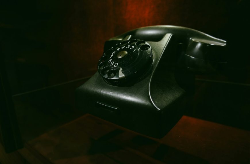 Vintage rotary dial telephone on a dark surface.
