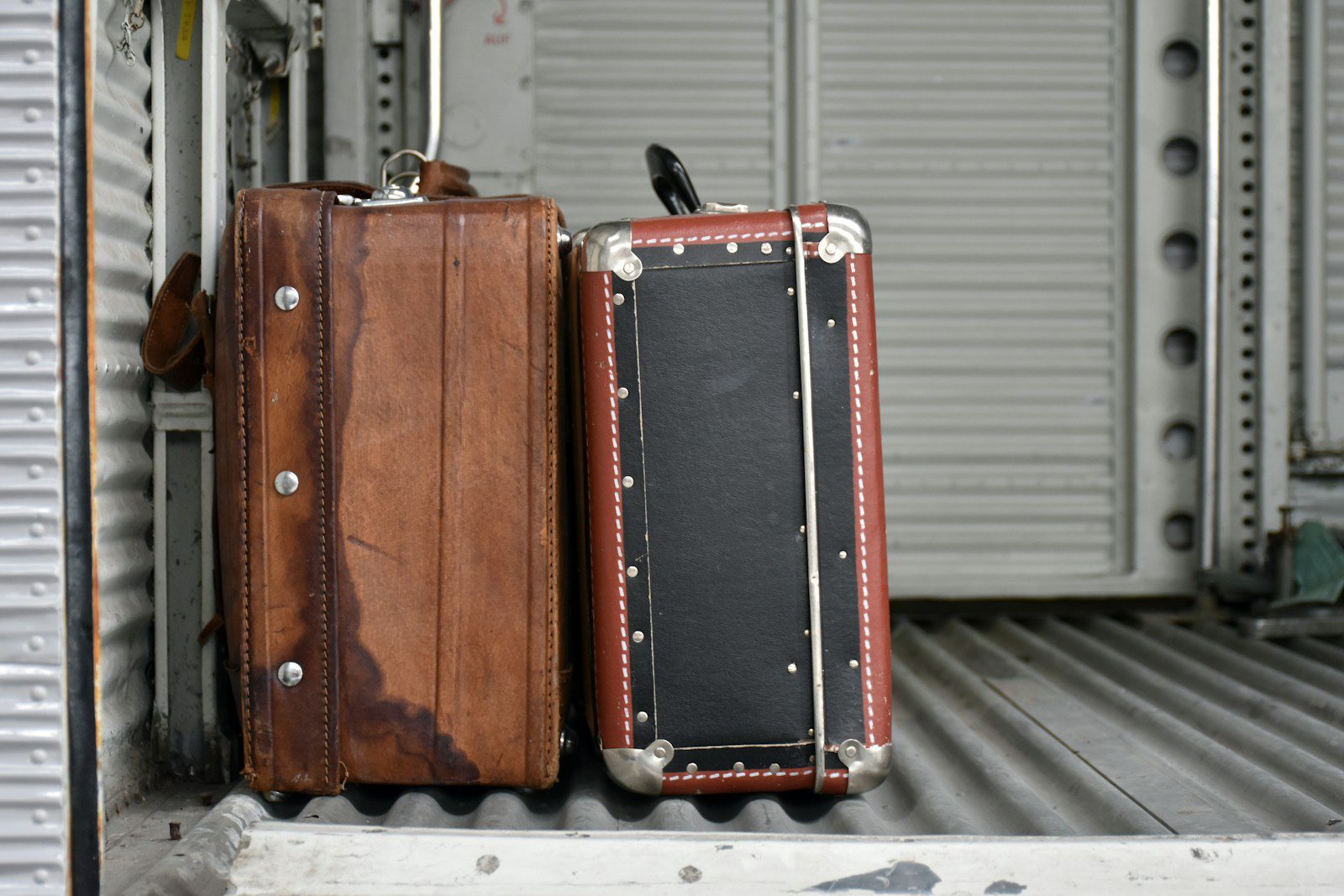 Two vintage suitcases on a ribbed surface.