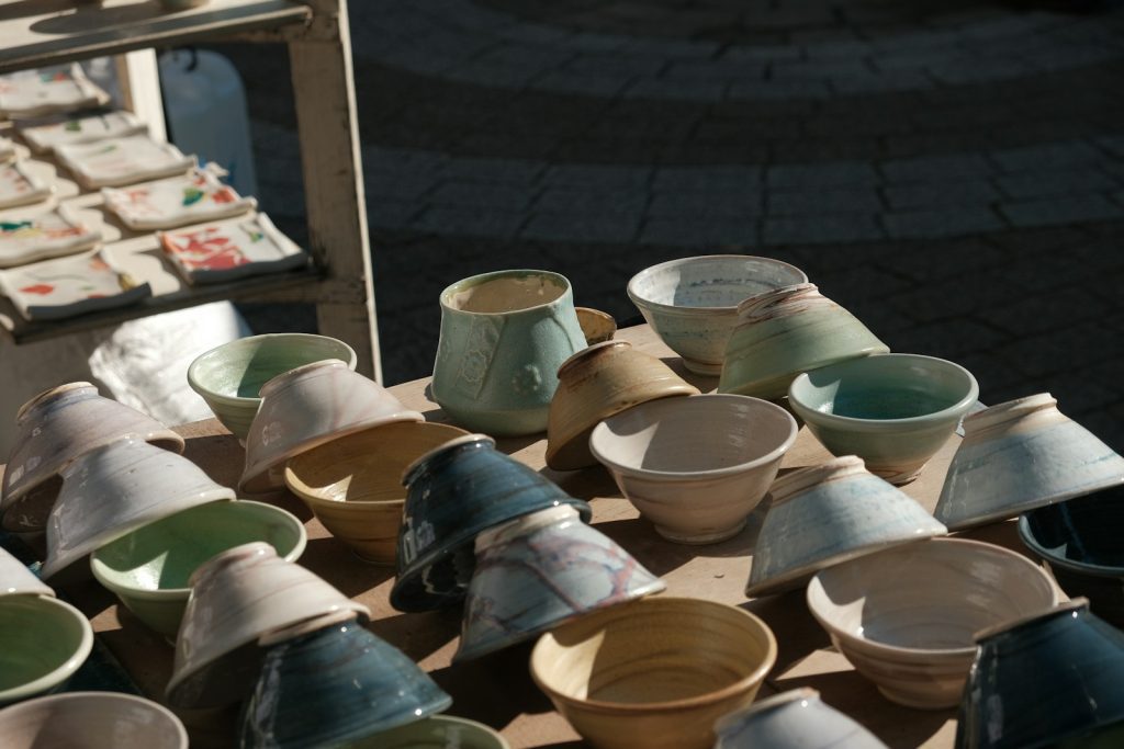 Assortment of ceramic bowls and cups displayed outdoors