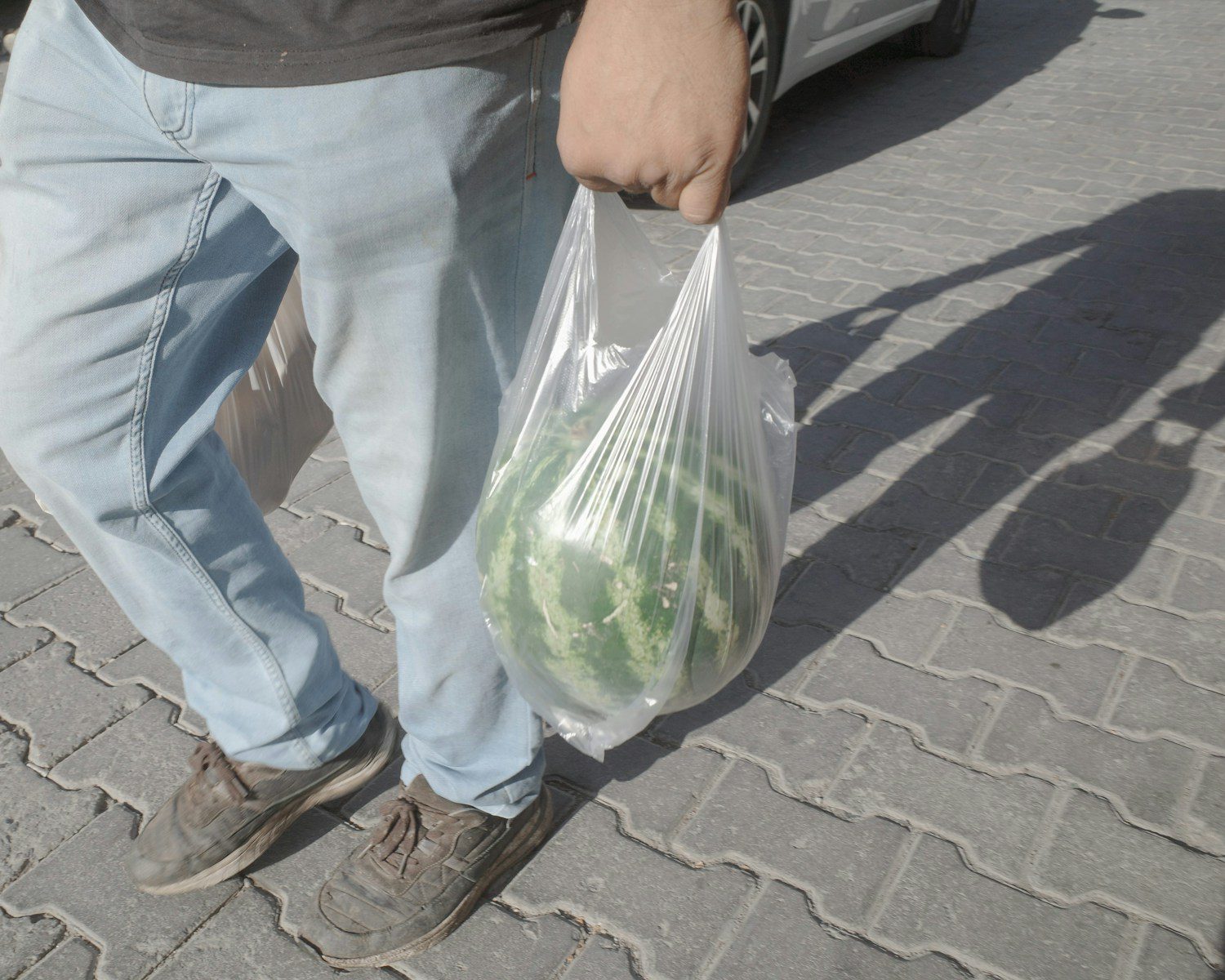 A man holding a bag of vegetables on a sidewalk