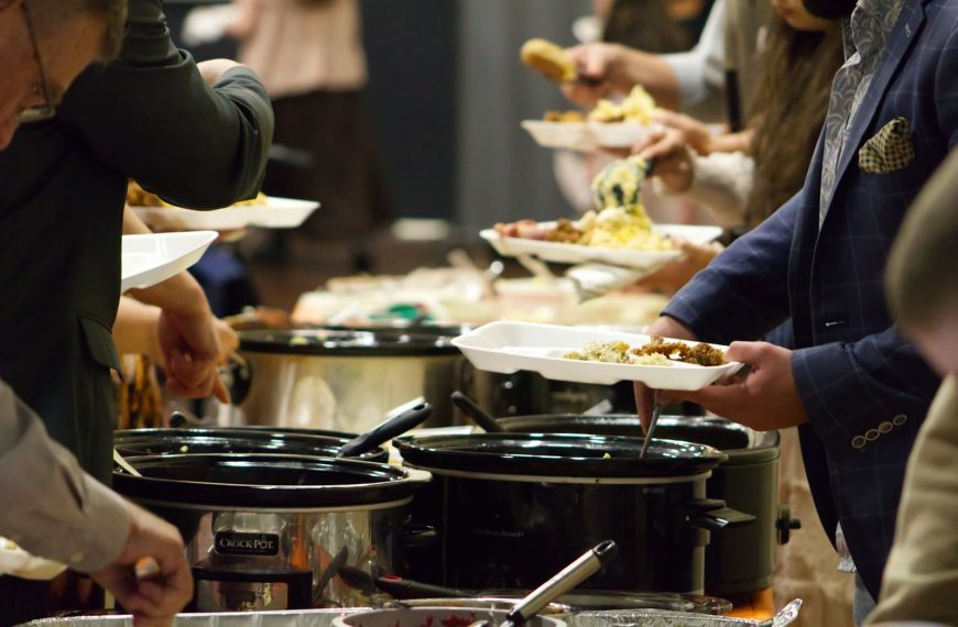 A group of people standing around a buffet line