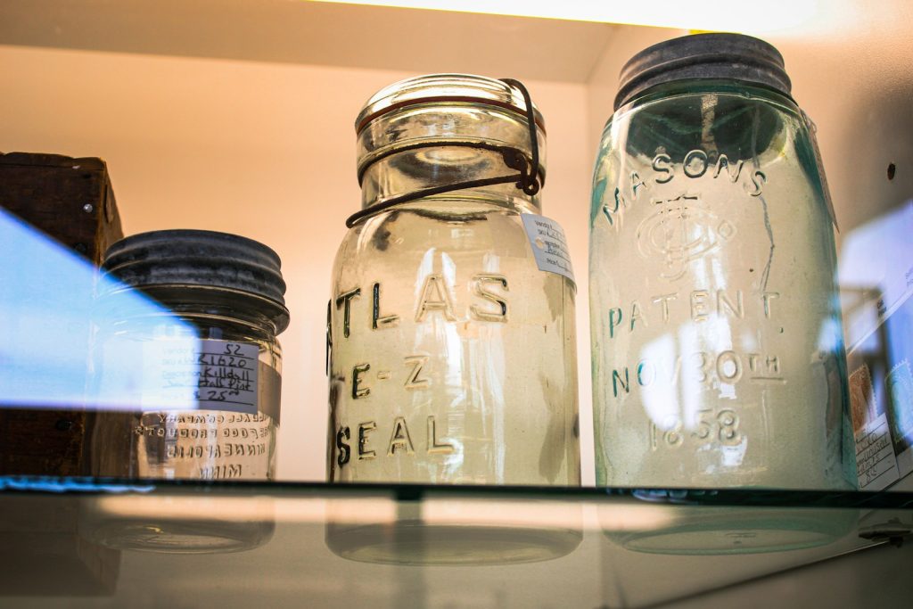 three glass jars are sitting on a shelf