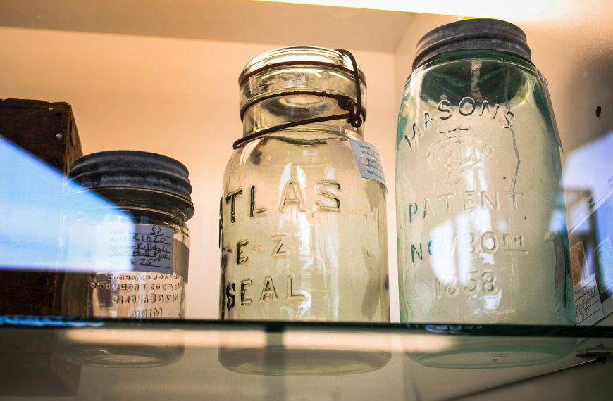 three glass jars are sitting on a shelf