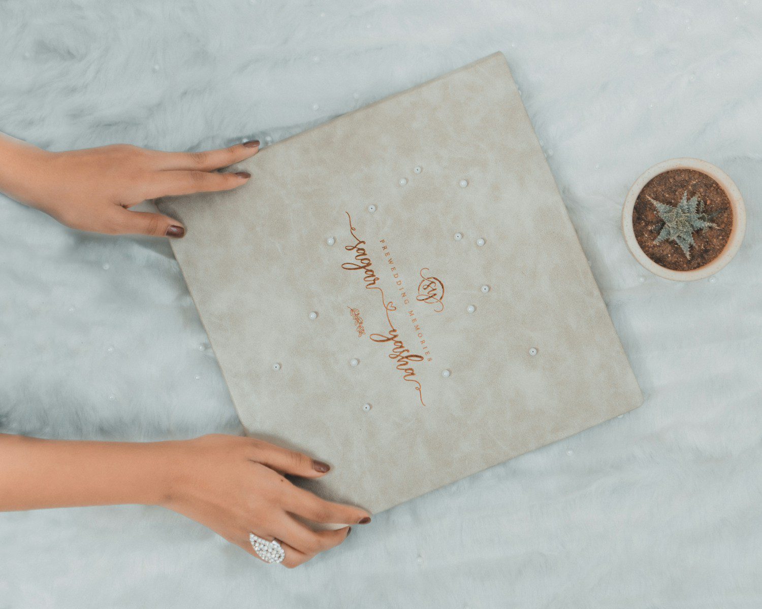 a woman's hands holding a wedding ring next to a box