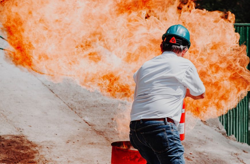 man in white shirt and blue denim jeans wearing black helmet standing on gray concrete road