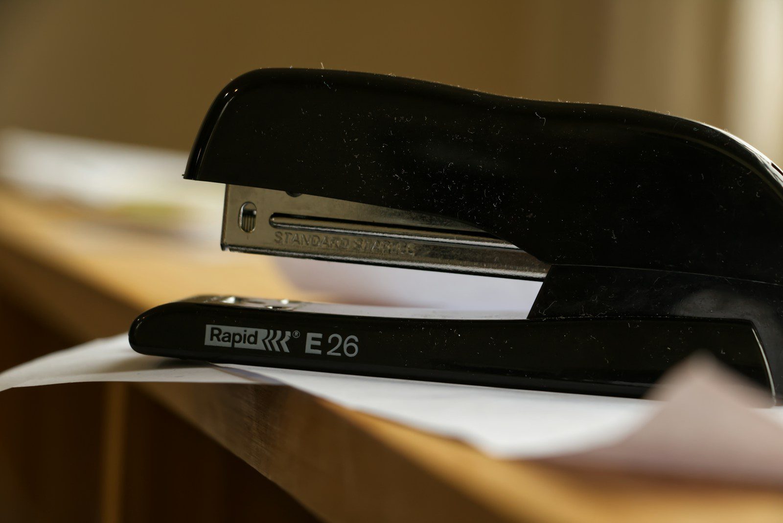 A black stapler rests on a desk with papers.