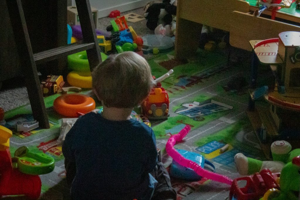a little boy sitting on the floor in a room full of toys