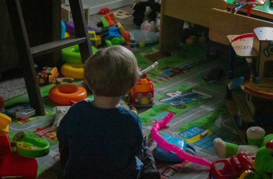 a little boy sitting on the floor in a room full of toys