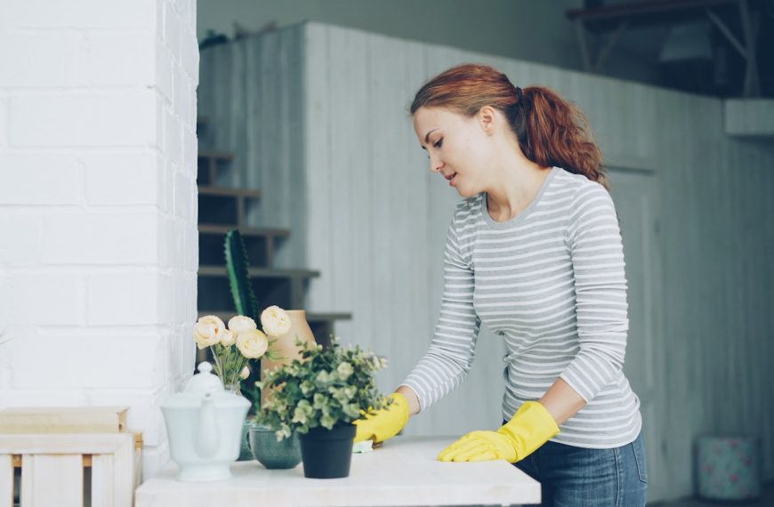 Woman in yellow gloves cleaning a table