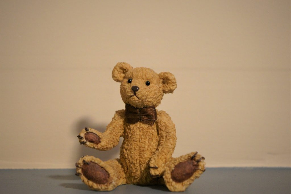 a brown teddy bear sitting on the floor