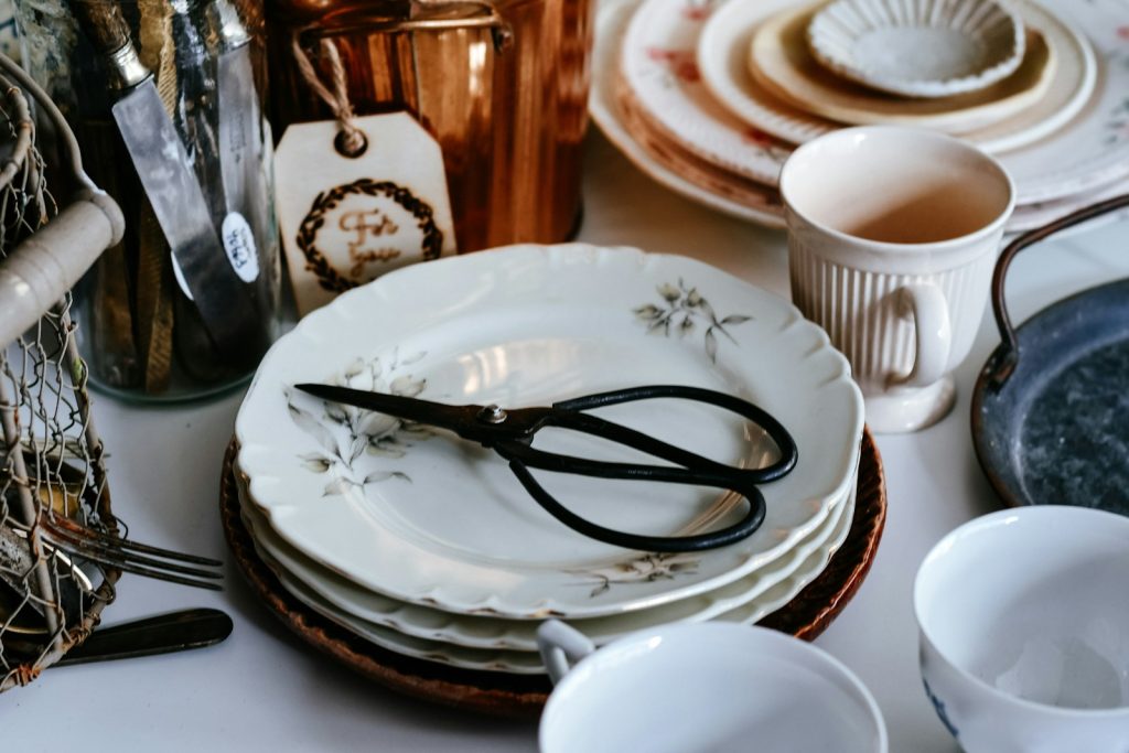 Stack of vintage plates with scissors and copper pot