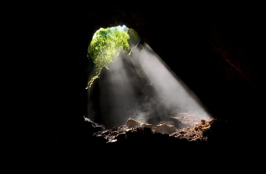 a light coming from a cave into a body of water