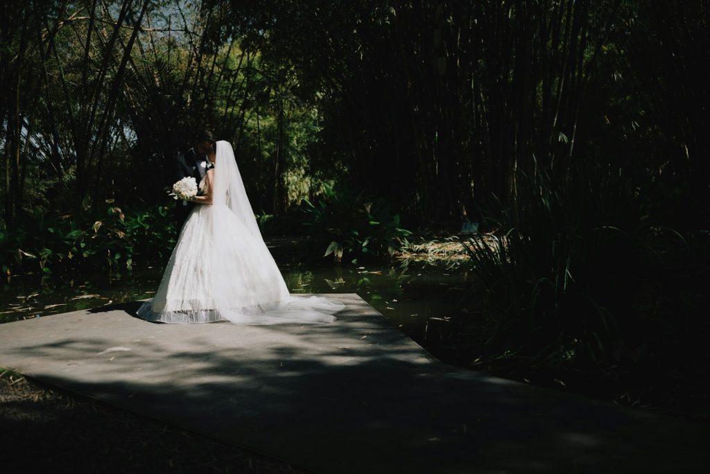 Bride in a white dress holding a bouquet outdoors.