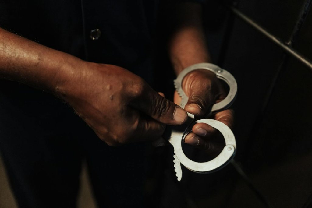 Close-up image of hands holding handcuffs, symbolizing punishment and crime.