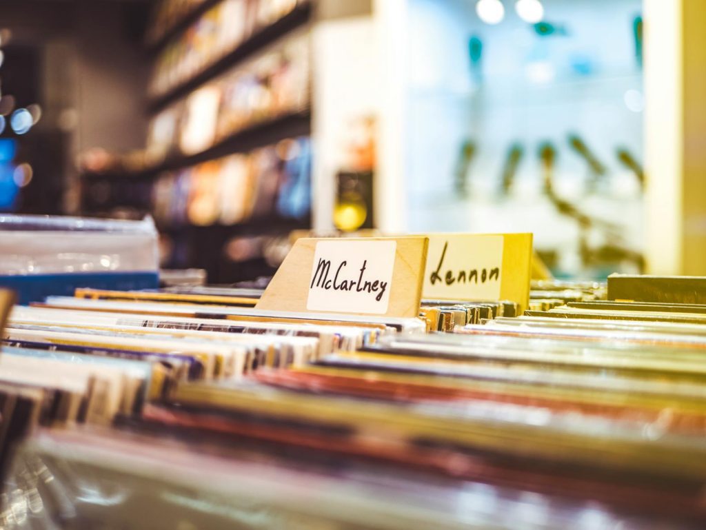 Colorful display of vinyl records in a music store, focusing on McCartney and Lennon sections.