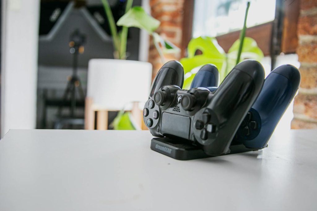 A wireless game controller resting on a charging dock in a modern indoor setting, showcasing gaming technology.