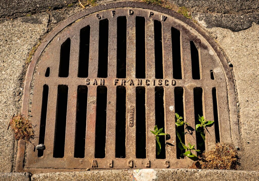 Close-up photo of a weathered drain cover embossed with 'San Francisco', showcasing urban texture and detail.