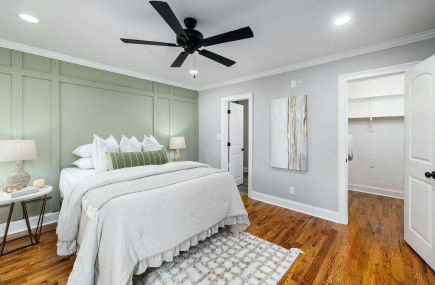 Stylish modern bedroom featuring elegant design with green accent wall and hardwood floors.