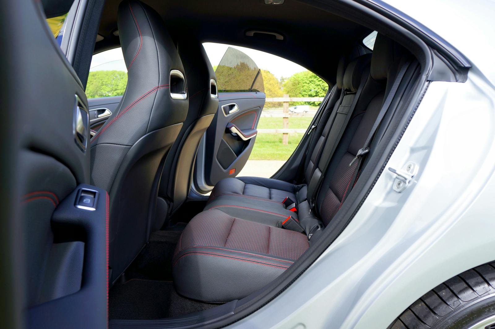 Elegant car interior featuring black leather seats with red stitching, showcasing modern luxury.