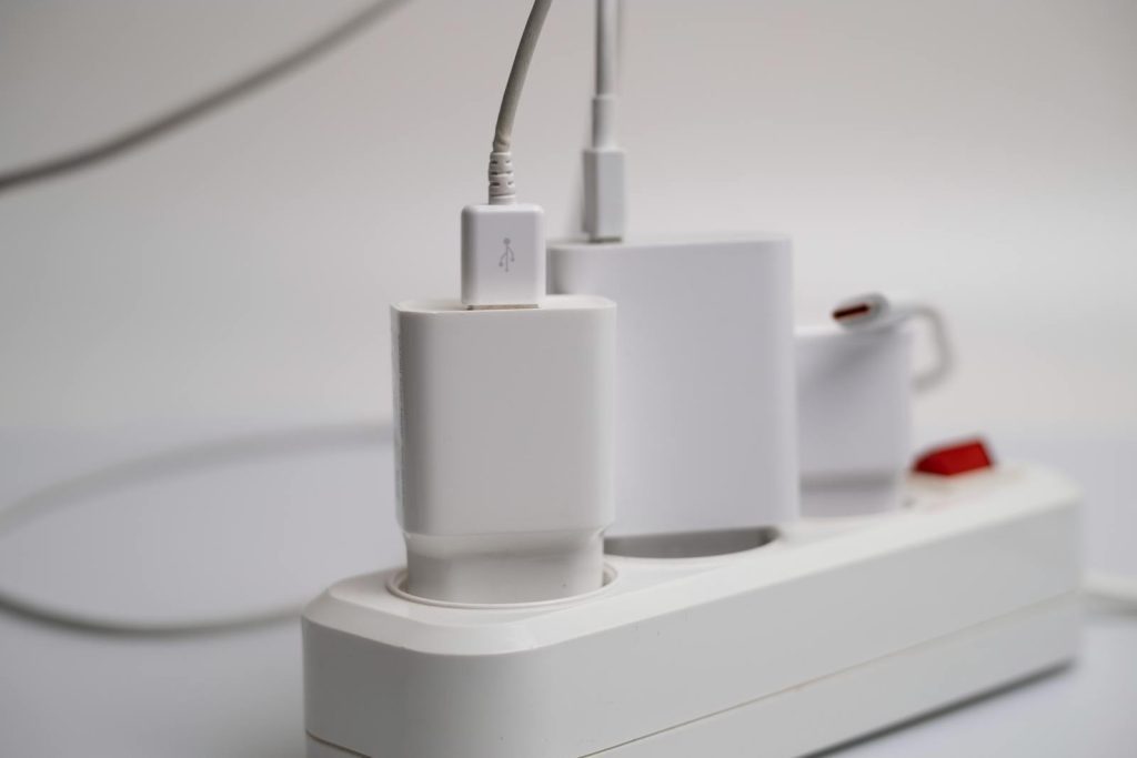 Minimalist composition of electronic device chargers connected to a power strip indoors.